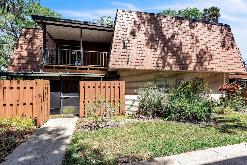 159 Sweetgum Ln, Port Orange, FL 32129 - view of front facade featuring brick siding, a balcony, fence, and mansard roof