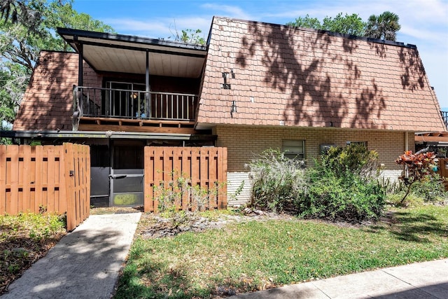 159 Sweetgum Ln, Port Orange, FL 32129 - view of front facade featuring brick siding, a balcony, fence, and mansard roof