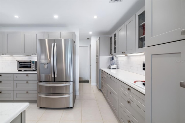 6940 W Country Club Dr N Unit V-77, Sarasota, FL 34243 - kitchen with stainless steel fridge with ice dispenser, gray cabinetry, glass insert cabinets, and light tile patterned floors
