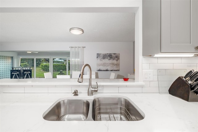 6940 W Country Club Dr N Unit V-77, Sarasota, FL 34243 - kitchen featuring a textured ceiling, light stone counters, a sink, and backsplash