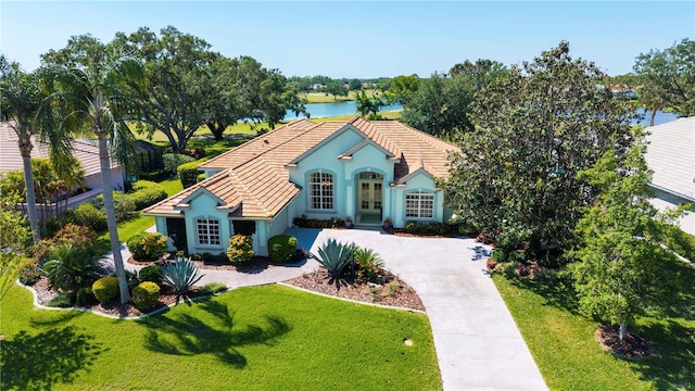 view of front of house with a tiled roof, french doors, driveway, a front yard, and stucco siding