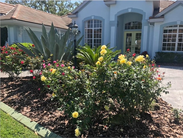 entrance to property featuring a tile roof, french doors, and stucco siding