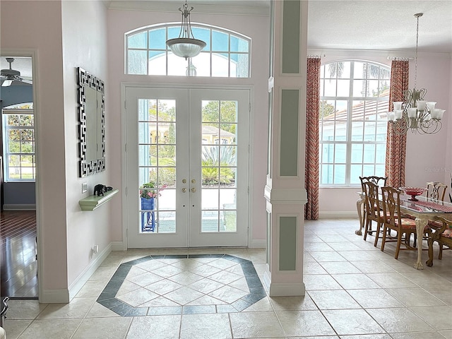 doorway to outside featuring a chandelier, ornamental molding, baseboards, french doors, and light tile patterned flooring