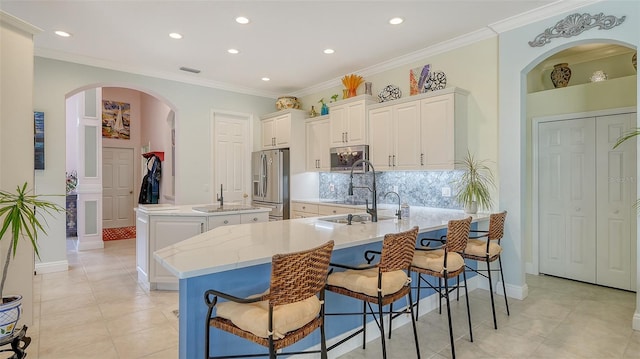 kitchen featuring appliances with stainless steel finishes, an island with sink, recessed lighting, a peninsula, and backsplash