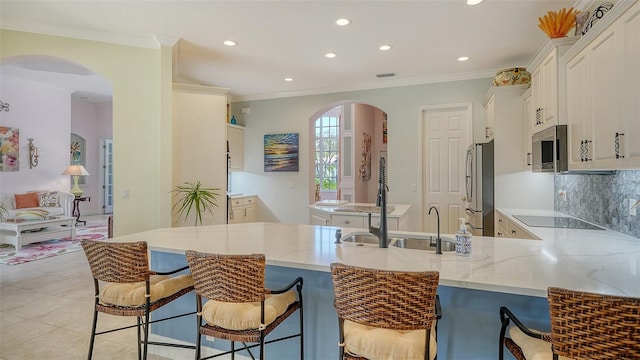 kitchen with stainless steel appliances, a peninsula, light stone counters, recessed lighting, and white cabinets