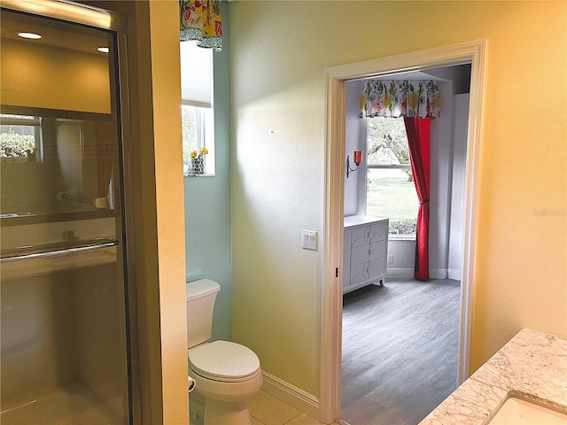 full bathroom with toilet, baseboards, a shower with door, and wood finished floors