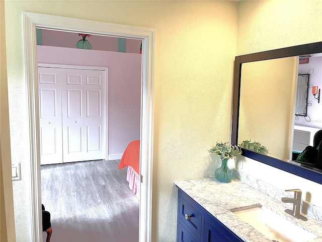 bathroom featuring wood finished floors, connected bathroom, vanity, and a textured wall