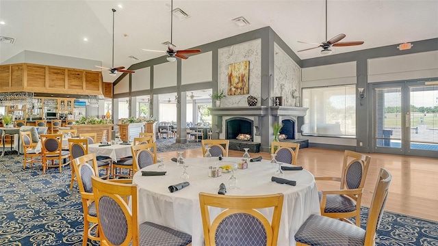 dining area featuring ceiling fan, high vaulted ceiling, a fireplace with raised hearth, and recessed lighting