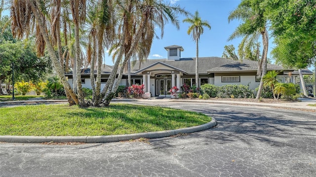 view of front of home with french doors, stucco siding, a front yard, and curved driveway