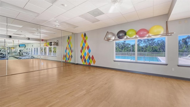 exercise room with wood finished floors, baseboards, and a drop ceiling