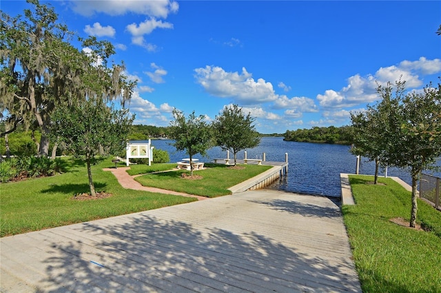 dock area with a boat ramp, a water view, and a lawn