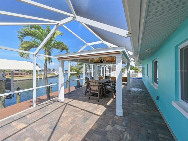 10016 Spoonbill Rd E, Bradenton, FL 34209 - view of patio with a ceiling fan, outdoor dining area, glass enclosure, and a water view