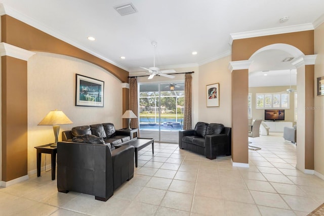 living room with a wealth of natural light, a ceiling fan, ornate columns, and visible vents