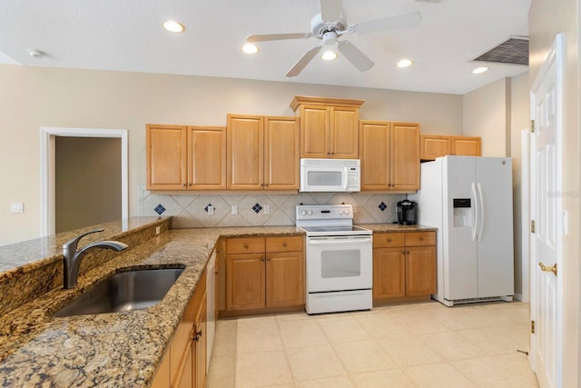 kitchen featuring backsplash, visible vents, light stone countertops, a sink, and white appliances
