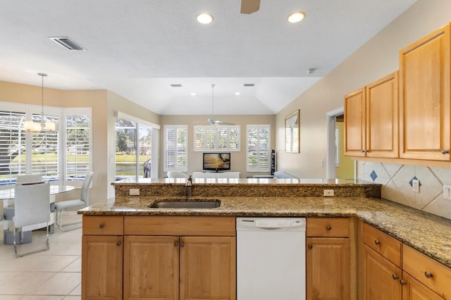 kitchen featuring white dishwasher, light stone countertops, a sink, decorative backsplash, and visible vents