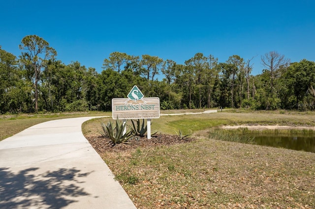 view of property's community featuring a yard, a water view, and a view of trees