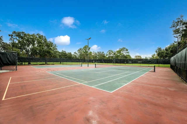 view of tennis court featuring fence and community basketball court