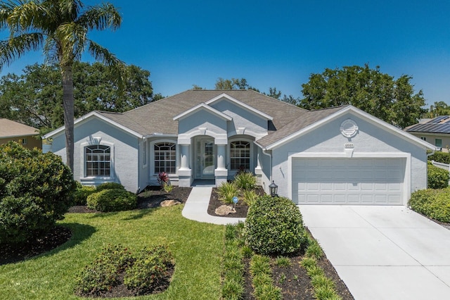 ranch-style house with a front lawn, roof with shingles, stucco siding, concrete driveway, and an attached garage