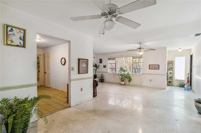 unfurnished living room with a ceiling fan, speckled floor, and visible vents