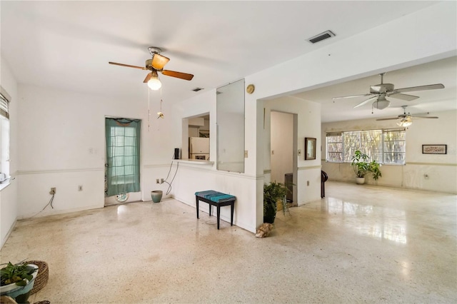 living room with a ceiling fan, visible vents, and speckled floor