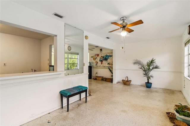 interior space with visible vents, a ceiling fan, and speckled floor