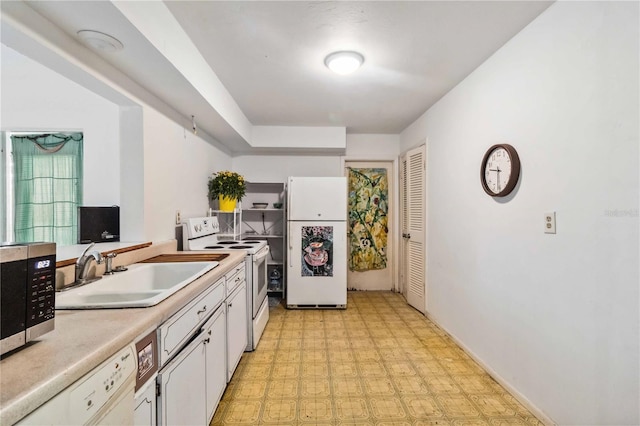 kitchen with a sink, light countertops, light floors, white appliances, and white cabinetry