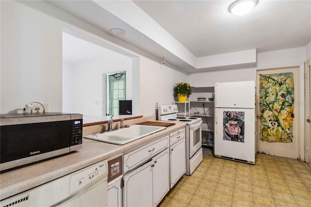 kitchen with white appliances, light floors, light countertops, white cabinets, and a sink