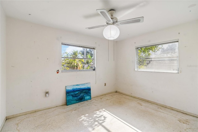 empty room featuring baseboards, plenty of natural light, and a ceiling fan