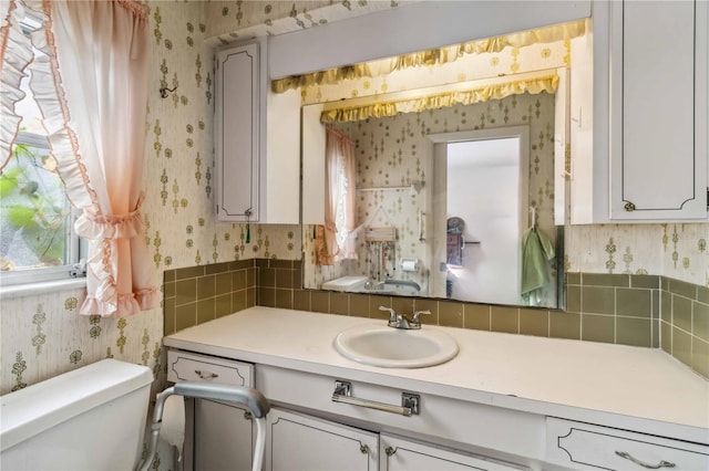 bathroom featuring vanity, toilet, and wallpapered walls