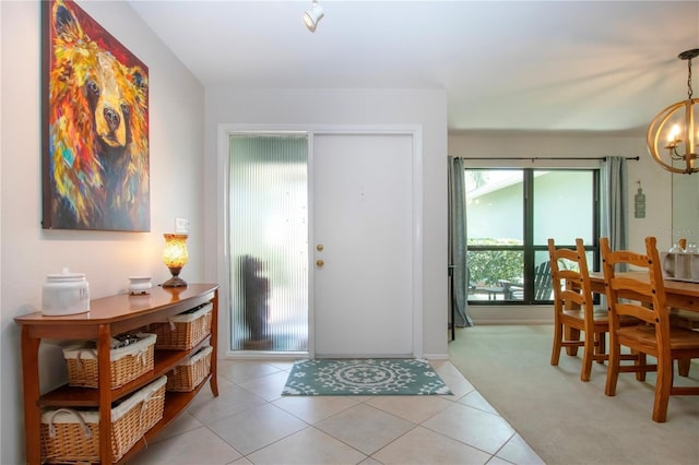 foyer featuring a chandelier, light carpet, baseboards, and light tile patterned floors