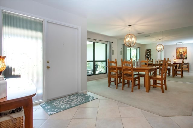 dining room featuring light colored carpet, a chandelier, light tile patterned floors, and baseboards