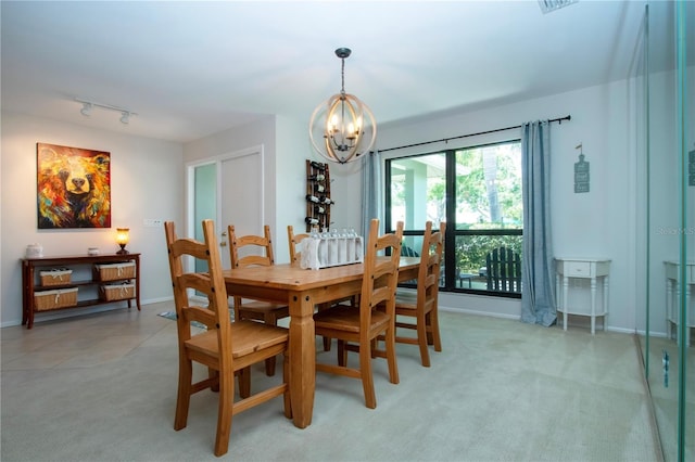 dining space with a chandelier, light colored carpet, baseboards, and track lighting