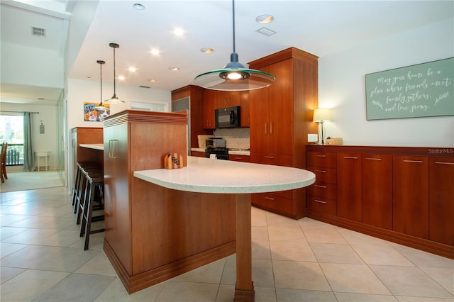 kitchen with black microwave, light countertops, a breakfast bar, hanging light fixtures, and tasteful backsplash