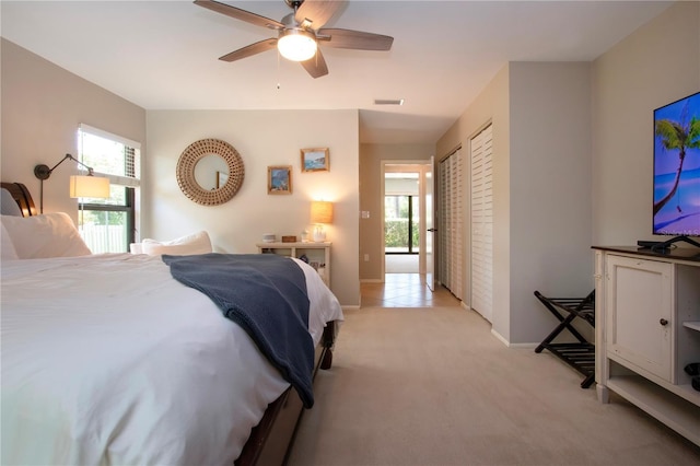 bedroom featuring light colored carpet, multiple windows, baseboards, and ceiling fan