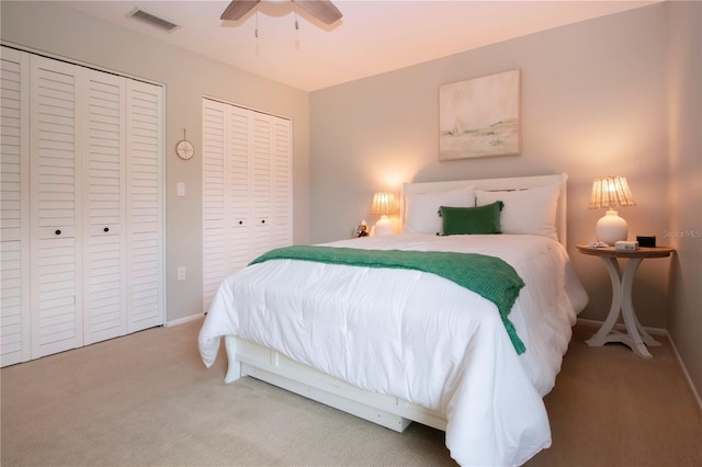 bedroom with two closets, carpet, ceiling fan, and baseboards