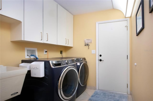 laundry room featuring washing machine and dryer, cabinet space, and light tile patterned floors