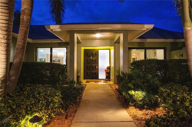 exterior entry at twilight featuring stucco siding