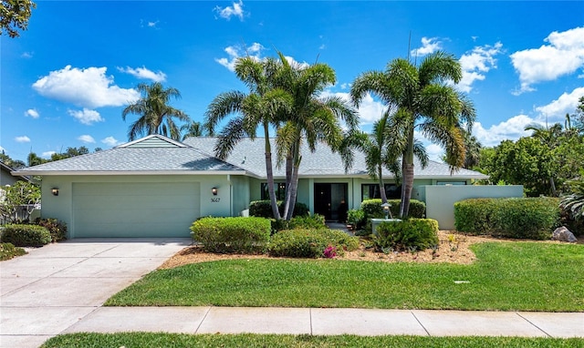ranch-style house with an attached garage, a front yard, concrete driveway, and stucco siding
