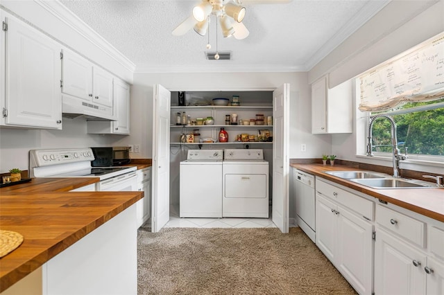 kitchen with white appliances, wooden counters, under cabinet range hood, washer and dryer, and a sink