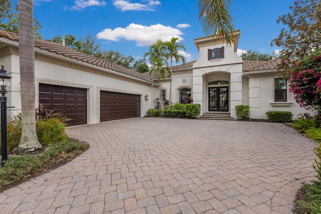 7532 Greystone St, Lakewood Ranch, FL 34202 - mediterranean / spanish home with decorative driveway, stucco siding, an attached garage, a tiled roof, and french doors