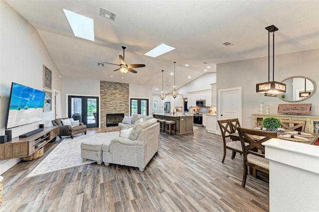 1103 134th St E, Bradenton, FL 34212 - living area featuring a skylight, high vaulted ceiling, wood finished floors, a ceiling fan, and a stone fireplace