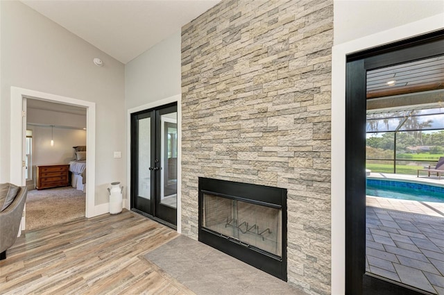 1103 134th St E, Bradenton, FL 34212 - unfurnished living room featuring wood finished floors, a stone fireplace, french doors, high vaulted ceiling, and baseboards