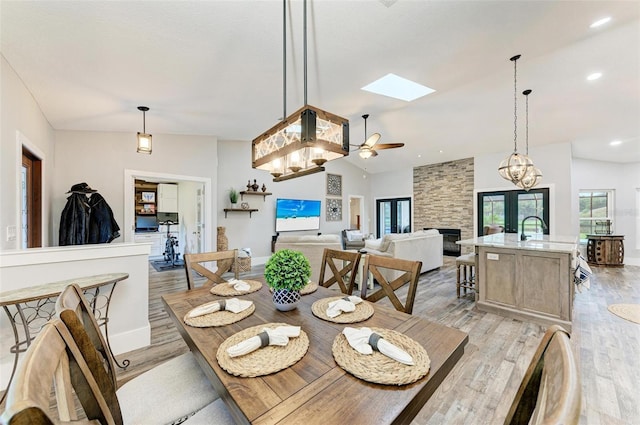 1103 134th St E, Bradenton, FL 34212 - dining room featuring a skylight, light wood-style floors, ceiling fan, and a stone fireplace