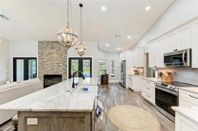 1103 134th St E, Bradenton, FL 34212 - kitchen with appliances with stainless steel finishes, french doors, light wood-type flooring, a large island with sink, and recessed lighting