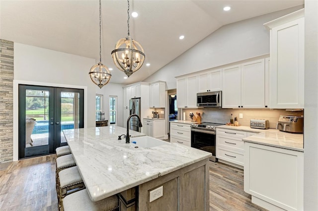 1103 134th St E, Bradenton, FL 34212 - kitchen featuring stainless steel appliances, a sink, french doors, light wood finished floors, and a chandelier