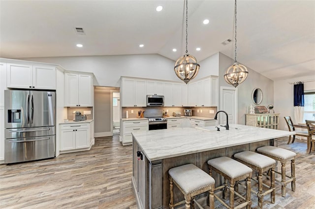 1103 134th St E, Bradenton, FL 34212 - kitchen featuring stainless steel appliances, a chandelier, light wood-style flooring, white cabinetry, and high vaulted ceiling