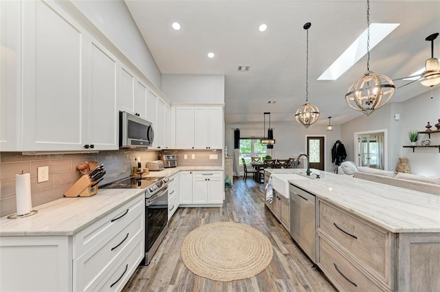 1103 134th St E, Bradenton, FL 34212 - kitchen with stainless steel appliances, a sink, open floor plan, a skylight, and light wood-style floors
