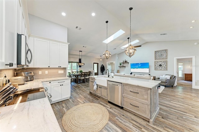 1103 134th St E, Bradenton, FL 34212 - kitchen with appliances with stainless steel finishes, open floor plan, a skylight, light wood-type flooring, and a sink