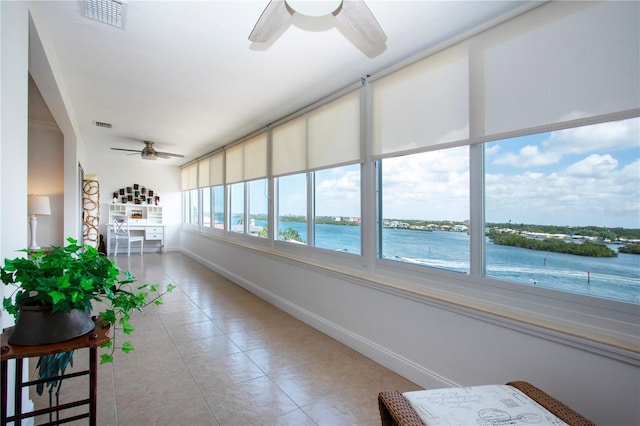 sunroom / solarium featuring a water view, visible vents, and baseboards
