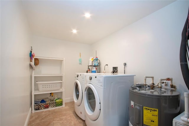 washroom with electric water heater, washer and clothes dryer, baseboards, and laundry area